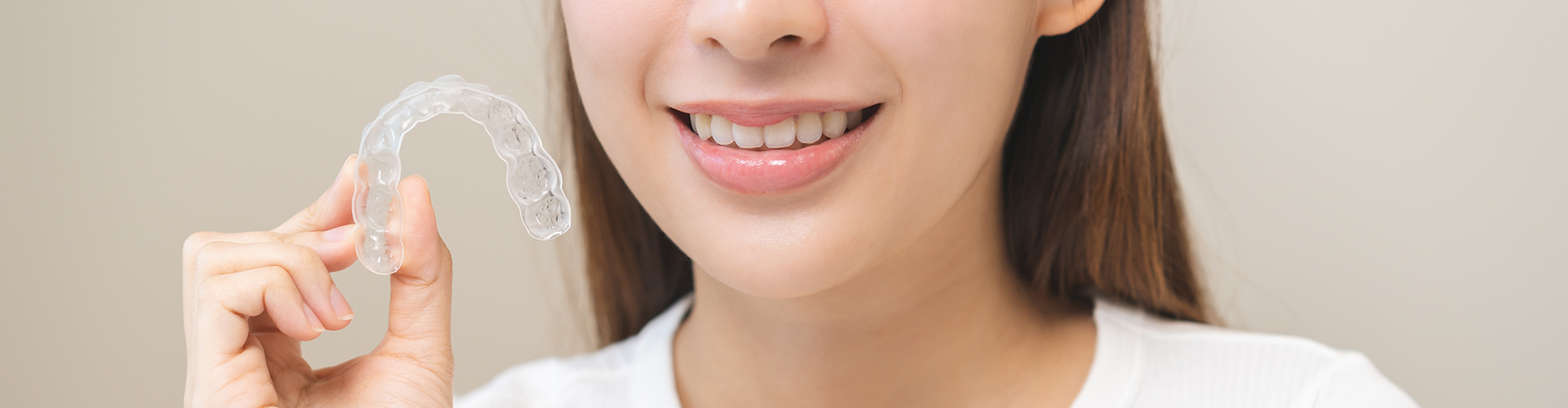 smiling woman holding clear aligner